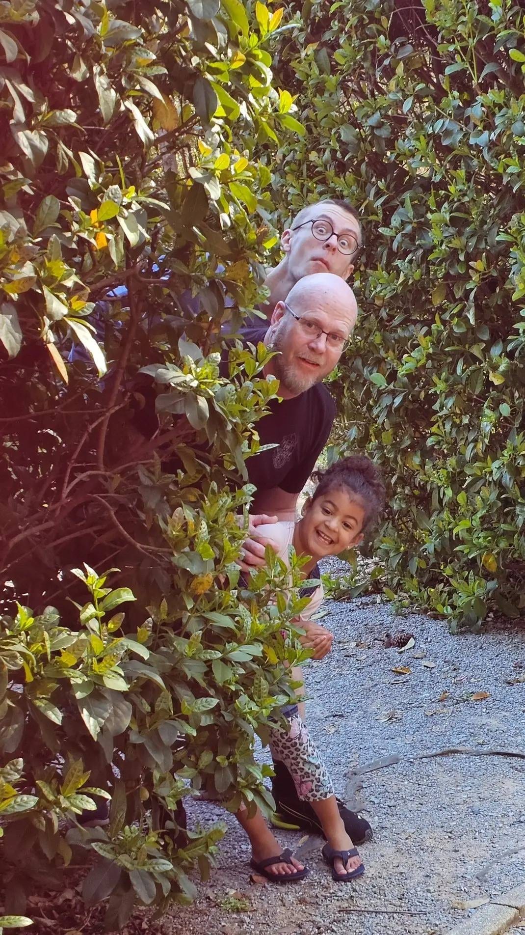 A playful family moment peeking through a leafy garden path