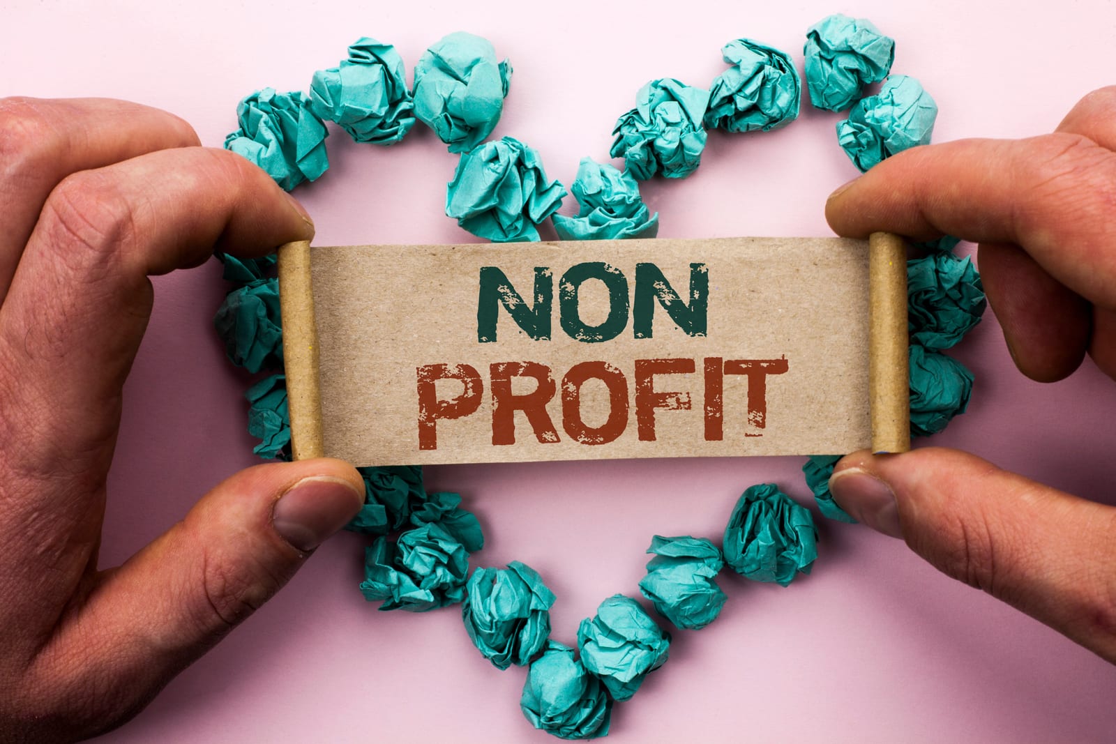 Hands holding a nonprofit sign surrounded by a paper heart